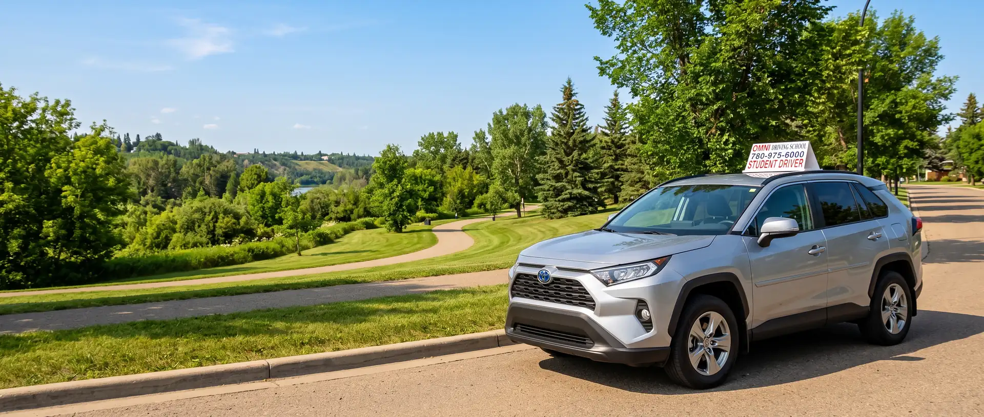 The Omni Driving School car on a road beside a green river valley park